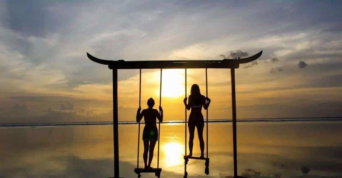 The Silhouette of Two Girls Standing on a Swing During Sunset on Gili Trawangan
