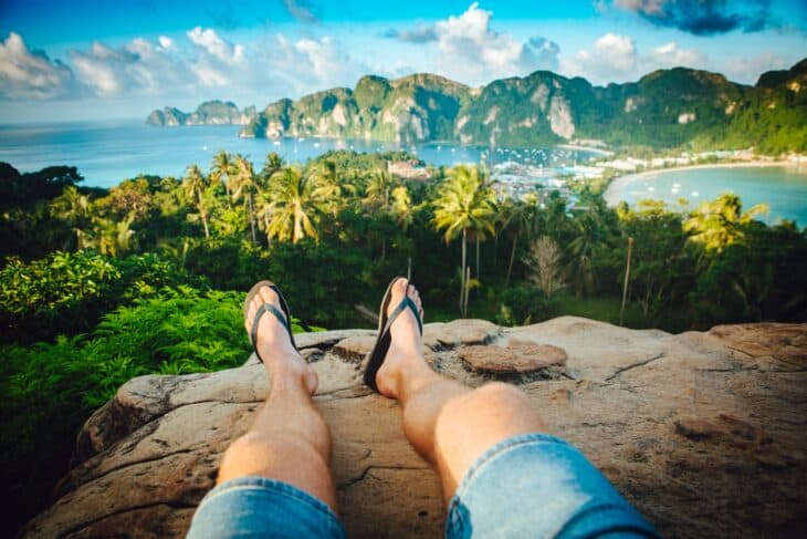 A man with flip flops sits on the cliff in Koh Phi Phi, Thailand.